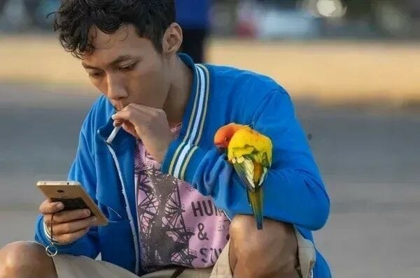 Man smoking cigarette in the presence of a bird